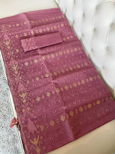 A  pink Banarasi silk saree with intricate gold floral and paisley motifs, laid out on a white tufted sofa next to a gray carpet.