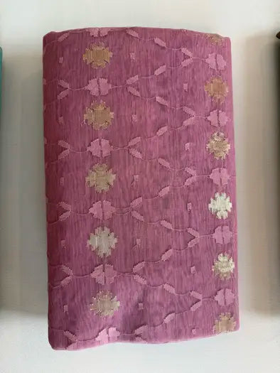 A folded piece of  pink brocade fabric with metallic gold and silver floral motifs, displayed on a light surface.