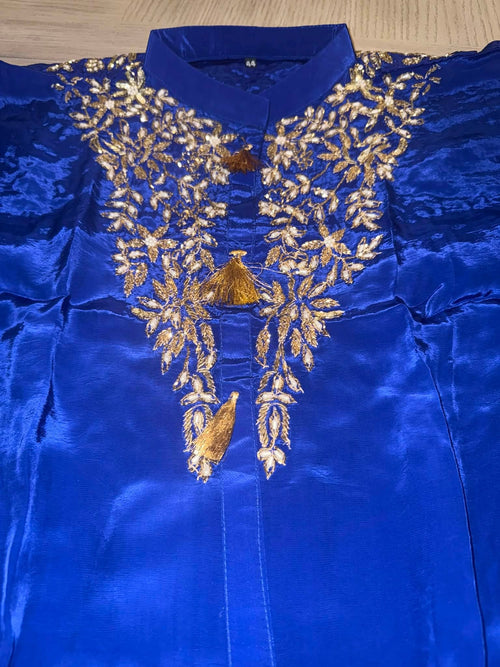 A royal blue satin kurta with intricate gold embroidery around the collar and chest, featuring a mandarin collar and a central tassel detail.