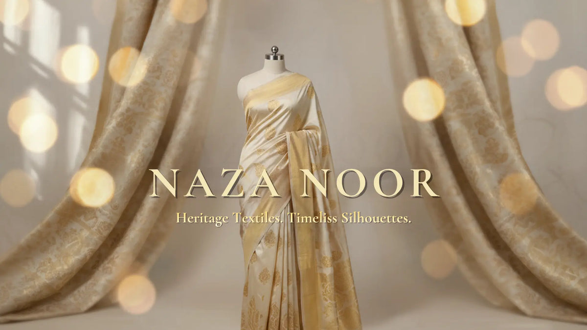 A draped gold saree displayed on a mannequin in front of ornate beige curtains with warm bokeh lights. The text 'NAZA NOOR' is overlaid in the center with the tagline 'Heritage Textiles Timeless Silhouettes.
